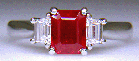 A fiery red ruby set with two trapezoid-cut diamonds in a hand-crafted platinum ring.