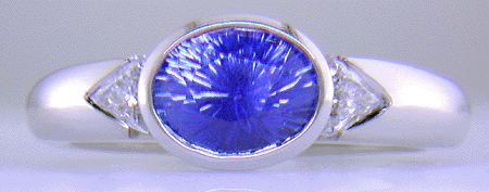Concave-faceted sapphire and trilliant diamonds in a custom platinum ring.