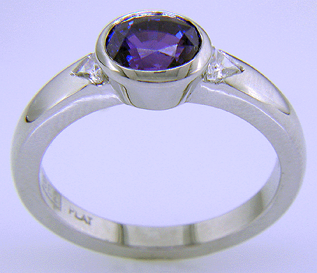 Side view of oval sapphire ring with trilliant diamonds crafted in platinum.