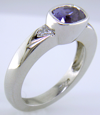 Violet sapphire with trilliant diamonds in a custom platinum ring.