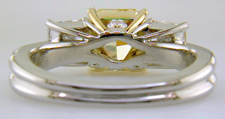 Inside view of custom platinum ring with yellow diamond set with two radiant-cut diamonds.