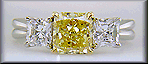 Fancy Intense Yellow diamond set with two radiant-cut diamonds in a custom platinum ring.