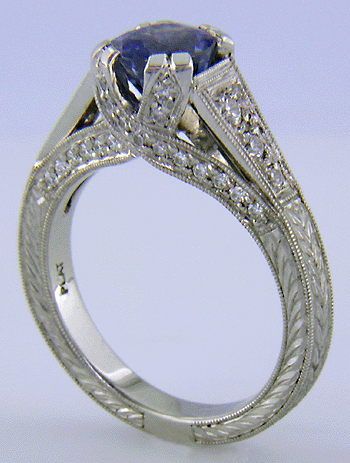 A bright sapphire set with 42 accenting diamonds in an engraved platinum ring.