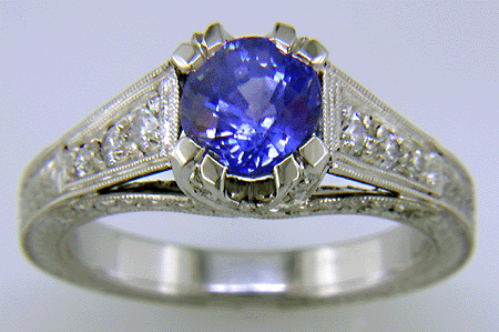 A bright sapphire set with 42 accenting diamonds in an engraved platinum ring.