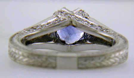 Inside view of bright sapphire set with 42 accenting diamonds in an engraved platinum ring.