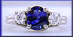 Platinum trellis ring set with an oval sapphire and two diamonds.