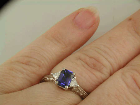 Sapphire ring with trilliant diamond and hand engraved platinum on the hand.