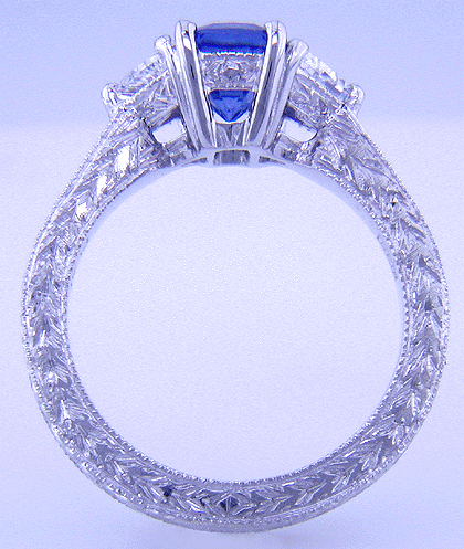 Side view of hand-engraved platinum ring with emerald-cut sapphire and diamonds.