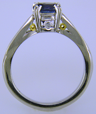 Side view of sapphire ring with two hidden diamonds and 18kt gold accents.