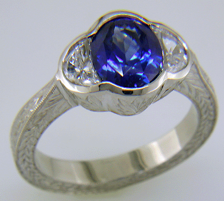 Oval saphire set with crescent moon diamonds in an engraved platinum ring. (J7269)