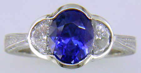 Oval saphire set with crescent moon diamonds in an engraved platinum ring. (J7269)