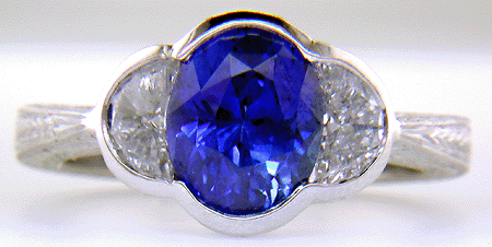 Oval saphire set with crescent moon diamonds in an engraved platinum ring. (J7269)