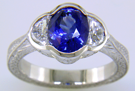 Oval saphire set with crescent moon diamonds in an engraved platinum ring. (J7269)
