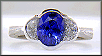 Oval saphire set with crescent moon diamonds in an engraved platinum ring.