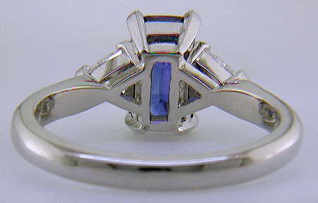 Inside view of hand-crafted platinum ring with a sriking emerald-cut sapphire and two sparkling trilliant diamonds.