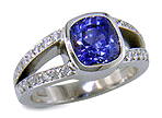 A bright cushion-cut sapphire set with accenting diamonds in a platinum ring. (J6654)