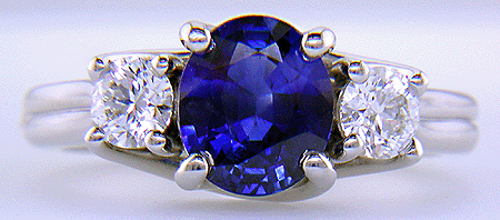 Platinum trellis ring set with an oval sapphire and two diamonds.