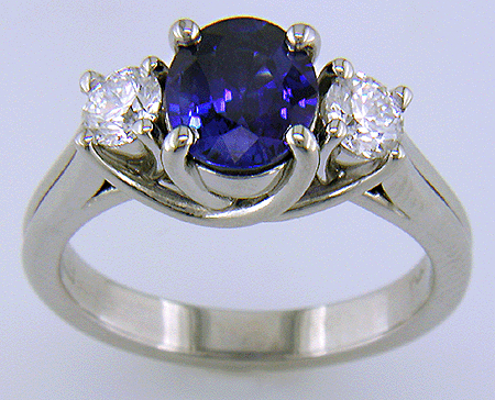 Platinum trellis ring set with an oval sapphire and two diamonds.