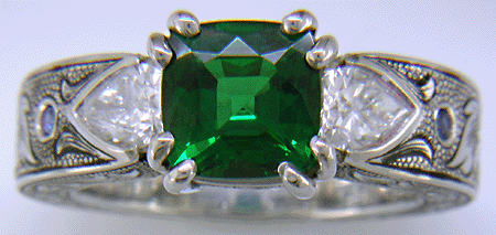 A cushion-cut Tsavorite garnet set in a beautifully hand crafted and engraved platinum ring.