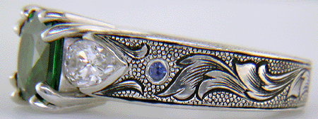 A cushion-cut Tsavorite garnet set in a beautifully hand crafted and engraved platinum ring.
