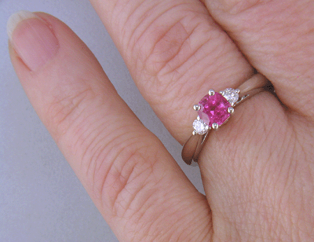 Cushion-cut Pink Sapphire set with two round diamonds in a handcrafted platinum ring. (J8597)