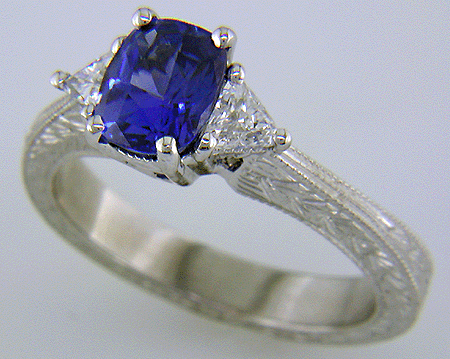 Cushion-cut sapphire and trilliant diamond hand-engraved platinum ring.