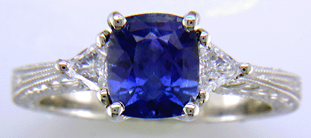Cushion-cut sapphire and trilliant diamond hand-engraved platinum ring.