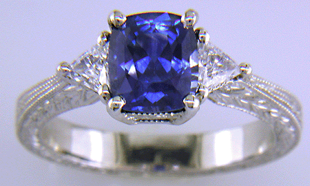 Cushion-cut sapphire and trilliant diamond hand-engraved platinum ring.