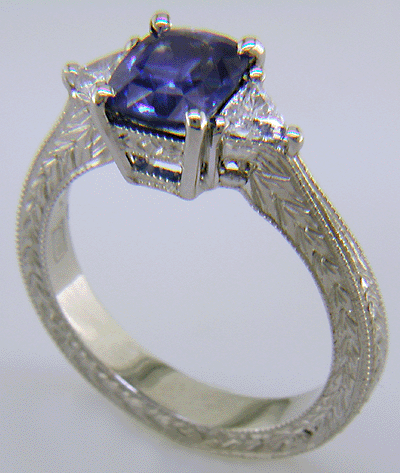 Cushion-cut sapphire and trilliant diamond hand-engraved platinum ring.