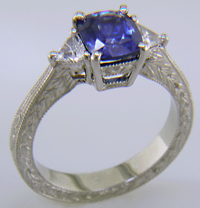 Cushion-cut sapphire and trilliant diamond hand-engraved platinum ring.