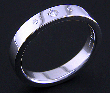 Platinum wedding band with burnish set diamonds.