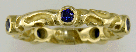 Richly carved 18kt gold band with five sparkling sapphires.