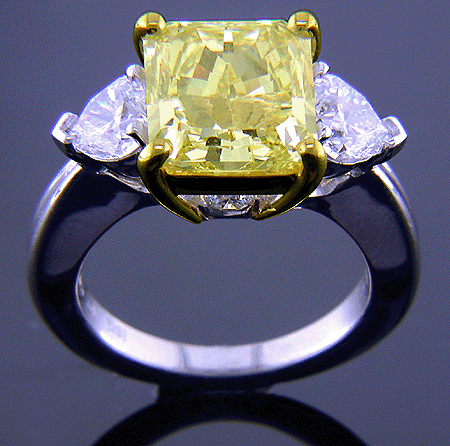 Yellow radiant-cut diamond with heart-shape diamonds in a custom platinum ring.