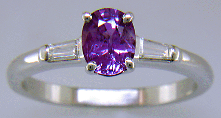 An oval Purple Sapphire set with tapered baguette diamonds in a custom platinum ring.