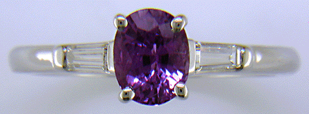 An oval Purple Sapphire set with tapered baguette diamonds in a custom platinum ring.