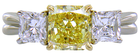 Fancy Intense Yellow diamond set with two radiant-cut diamonds in a custom platinum ring.