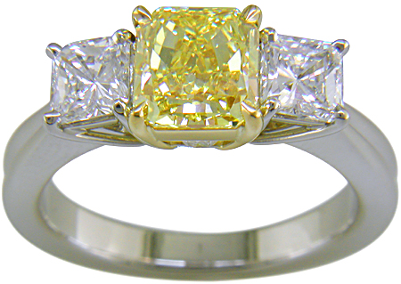 Fancy Intense Yellow diamond set with two radiant-cut diamonds in a custom platinum ring.