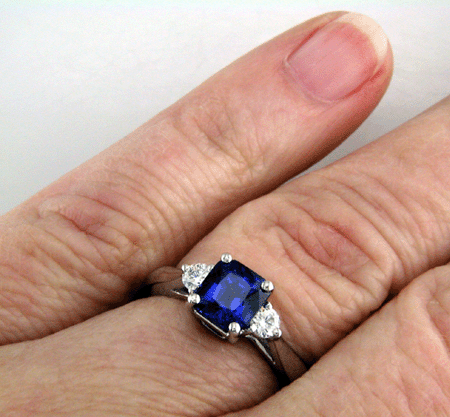 Emerald-cut sapphire set with two round diamonds in a handcrafted platinum ring. (J8540)