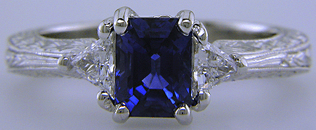 Hand engraved emerald-cut sapphire and trilliant diamond ring in platinum.
