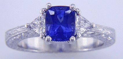 Hand engraved cushion sapphire and trilliant diamond ring in platinum.