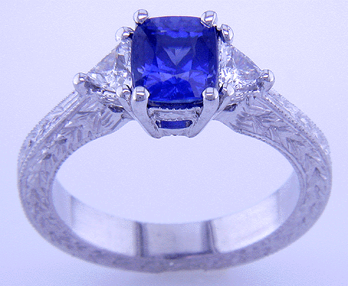 Hand engraved cushion sapphire and trilliant diamond ring in platinum.