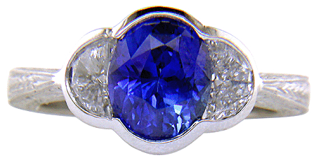 Oval sapphire set with crescent moon diamonds in an engraved platinum ring. (J7269)