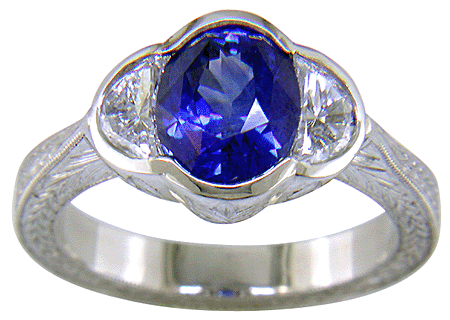 Oval sapphire set with crescent moon diamonds in an engraved platinum ring. (J7269)