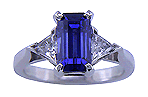 Emerald-cut sapphire set in a platinum ring with trilliant diamonds.