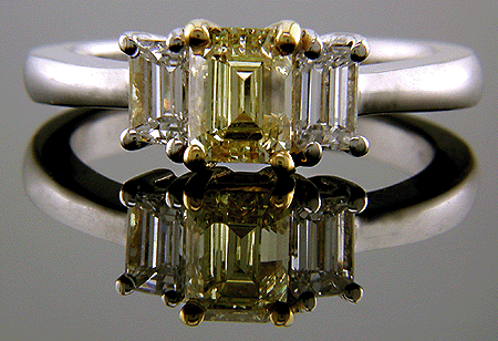 Fancy Yellow diamond with emerald-cut side diamonds in a platinum ring.