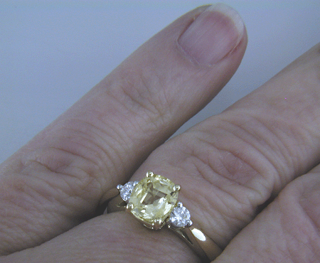 Cushion-cut Yellow Sapphire set with two brilliant-cut diamonds in a handcrafted 18kt gold and platinum ring.