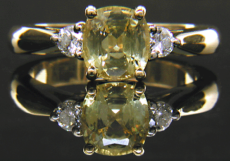 Cushion-cut Yellow Sapphire set with two brilliant-cut diamonds in a handcrafted 18kt gold and platinum ring.